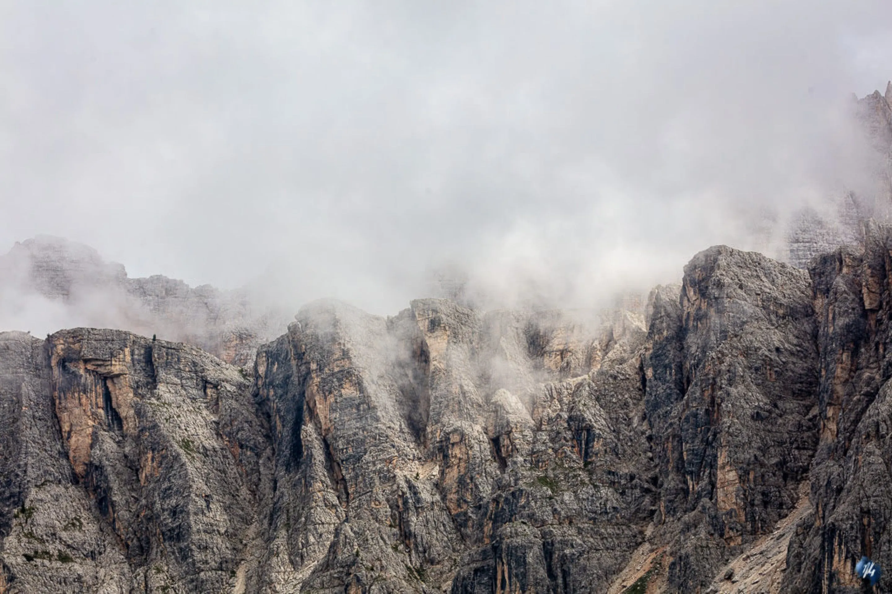 Rock formations disappearing into dense Alpine fog