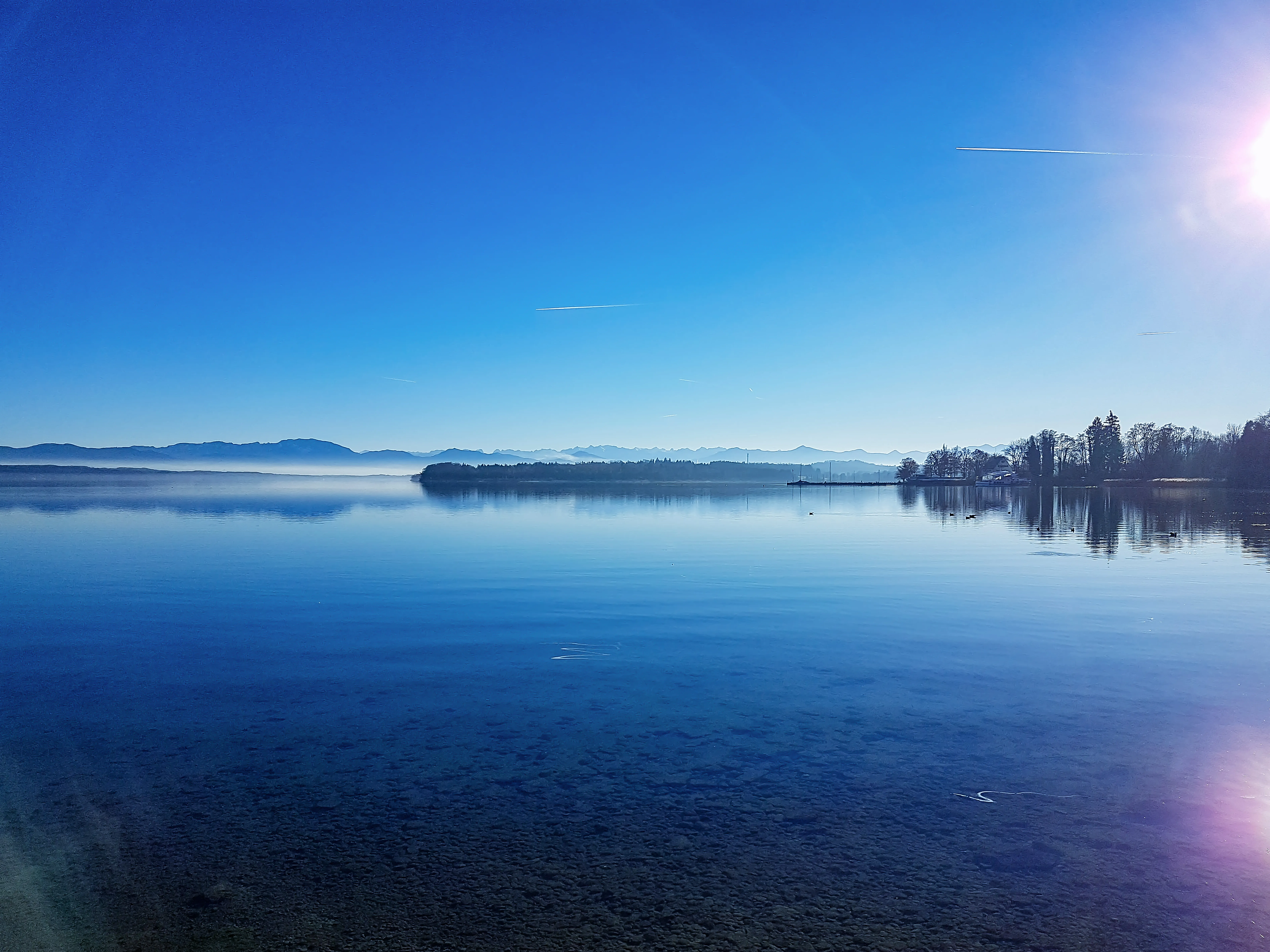 A wintry shoreline at Lake Starnberg beneath a bright sky